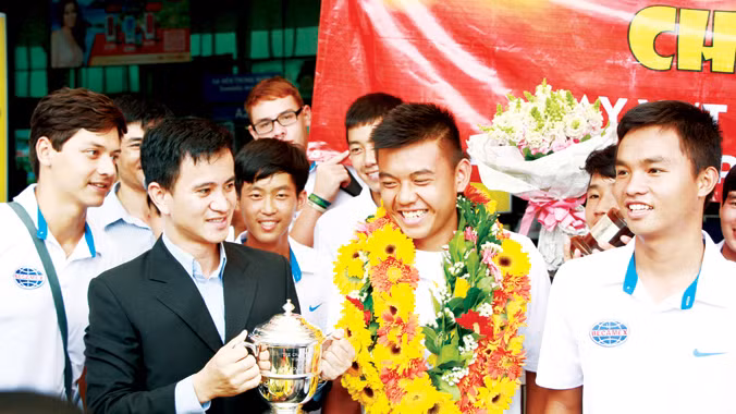 Lý Hoàng Nam (giữa) trong vòng vây người hâm mộ và lãnh đạo Becamex tại sân bay Tân Sơn Nhất. Ảnh: Ngô Tùng