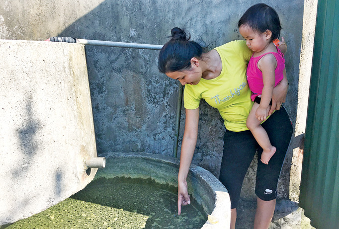 Từ khi dự án mỏ sắt Thạch Khê (Hà Tĩnh) khởi công, nguồn nước ở các xã bị cạn kiệt, bà Trương Thị Tuyết (thôn Liên Hải, Thạch Hải) bên những can nước mưa gia đình vừa tích trữ được. Ảnh: Minh Thùy.