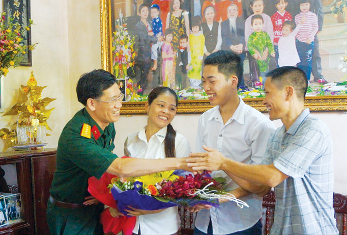 Đại tá Cao Trung Hà, Phó Chủ nhiệm Chính trị Học viện Kỹ thuật Quân sự tới nhà chúc mừng tân thủ khoa Lê Thanh Lâm​. Ảnh: N.M.
