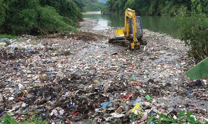 Hình ảnh máy xúc gạt rác xuống suối khiến người dân bức xúc. Ảnh: Chương Nhàn.