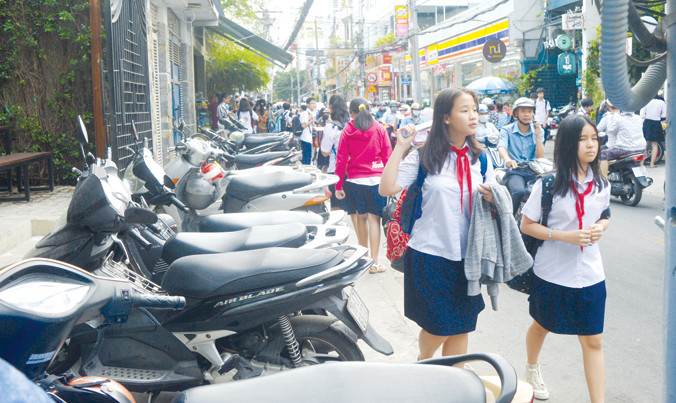 Tại TPHCM, vỉa hè bị chiếm làm nơi đậu xe khiến người đi bộ bị dồn xuống lòng đường. Ảnh: PV.