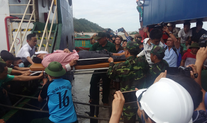 Một thuyền viên kiệt sức được cáng lên bờ.