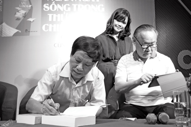 Vũ Công Chiến ký tặng sách trong buổi ra mắt “Hồi ức lính” năm ngoái. Bên cạnh là vợ anh và nhà văn Ngô Thảo. Ảnh: Nguyễn Đình Toán.