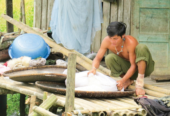 Một người A Rem đang đưa bao gạo còn lại ra phơi hi vọng còn dùng được trong mấy ngày tới.