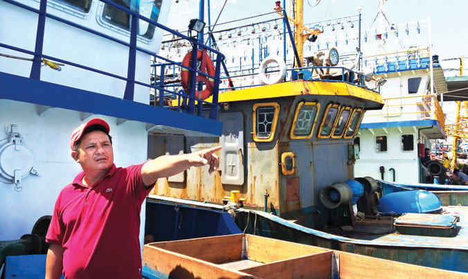 Thuyền trưởng Lê Văn Thãi từng tham gia tổ đội đi giữ biển. Bên cạnh anh là con tàu mục nát của ông Nguyễn Văn Lý. Ảnh: PV.