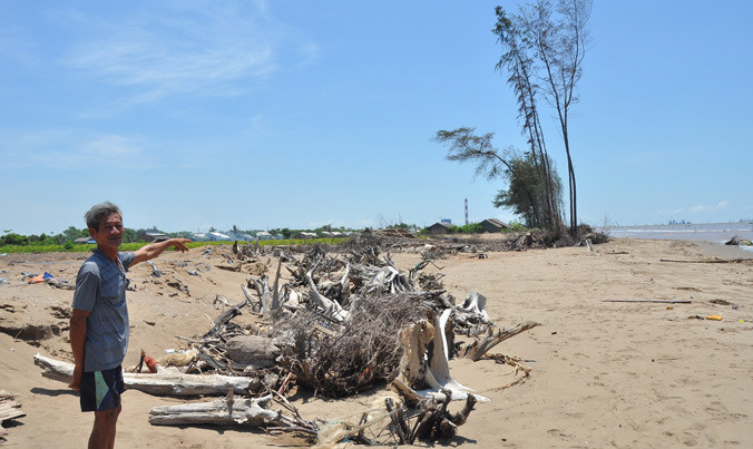 Ông Danh Văn Mỡ ở ấp Hồ Thùng, xã Đông Hải, (Duyên Hải, Trà Vinh) chỉ trên bãi cát đã cuốn mất nhà và hàng dương. Ảnh: Hòa Hội.