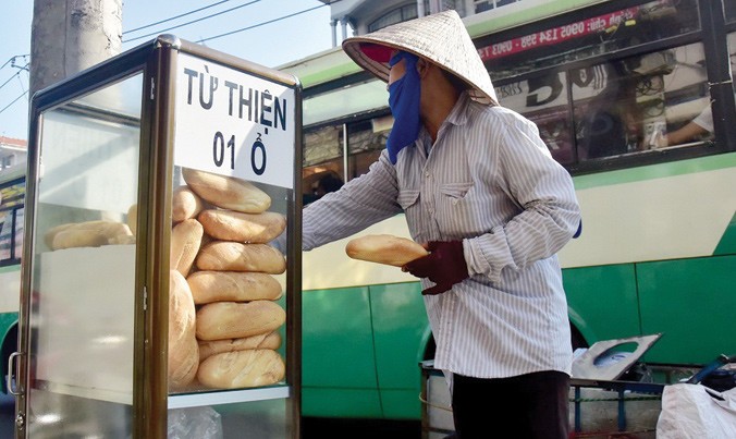 Một người mua ve chai đang lấy bánh mì từ thiện.