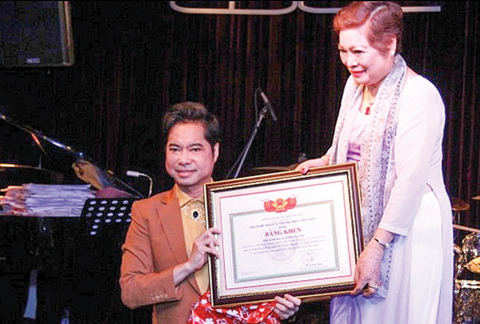 Ca sĩ Ngọc Sơn dâng tặng Bằng khen cho mẹ với tất cả tấm lòng kính trọng. Ảnh: Tử Văn.