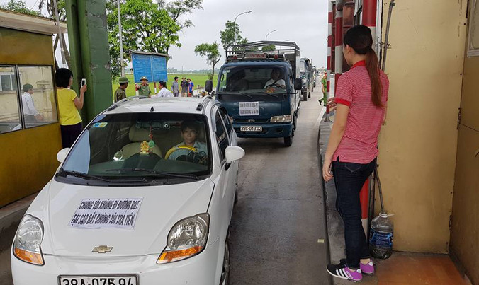 Người dân dùng xe ô tô dán logo, dàn hàng phản đối việc thu phí tại trạm thu phí cầu Rác. 