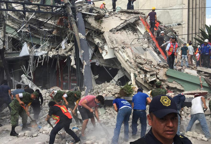 Đào bới, tìm kiếm người sống sót trong tòa nhà đổ sập. Ảnh: AP.