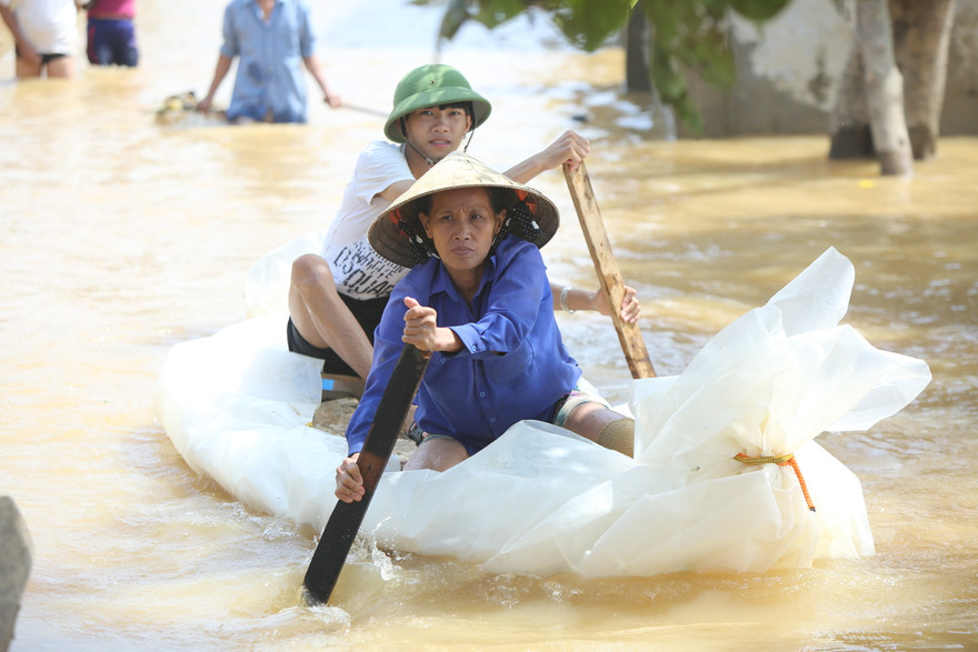 Người dân vùng lũ Quảng Bình chèo bè tự chế ra nhận hàng cứu trợ. Ảnh: Trọng Tài