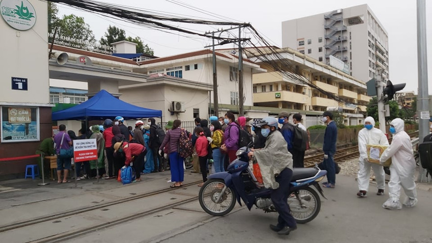 Người dân đến thăm khám, đưa đồ tiếp tế cho người nhà phải xếp hàng dài đo thân nhiệt trước khi vào bệnh viện Bạch Mai (Hà Nội)