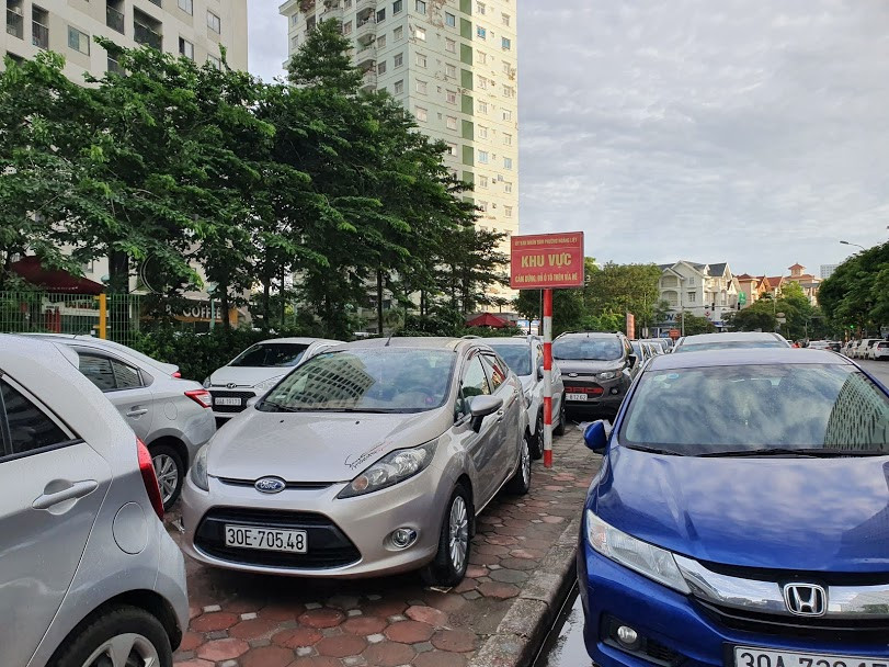 Việc trông giữ ô tô tại bãi xe được cấp tạm trên vỉa hè vẫn ngang nhiên diễn ra...