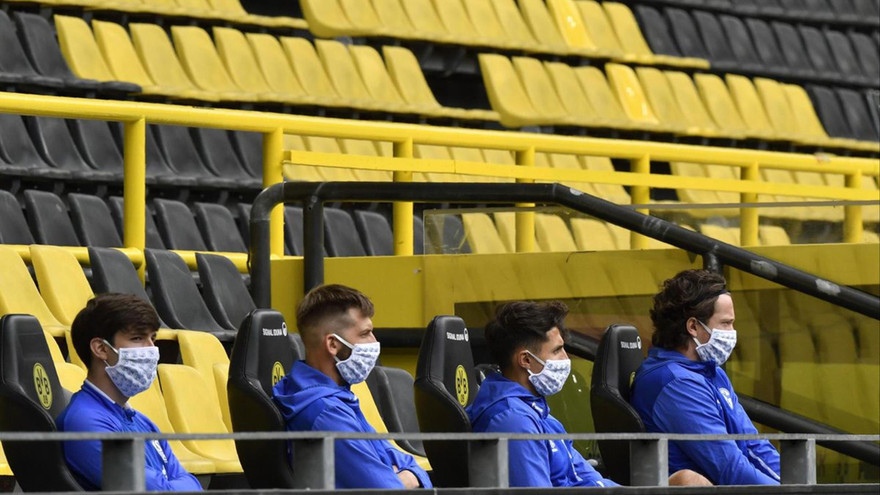 Các cầu thủ dự bị ngồi cách nhau 1,5m trên khán đài không có khán giả trong ngày Bundesliga trở lại thi đấu