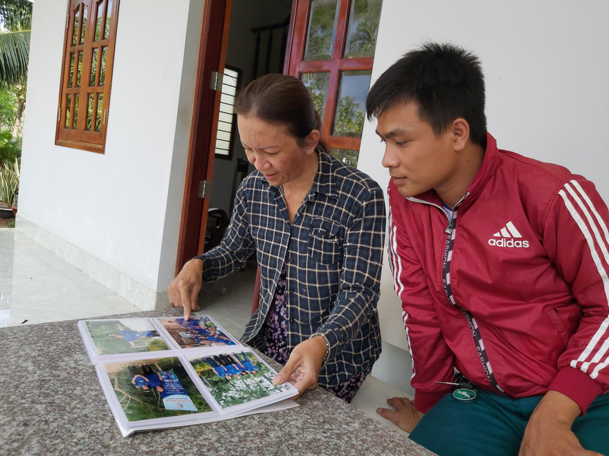  Bà Mai Thị Kim Chi lật giở từng trang album hình kỷ niệm với sinh viên tình nguyện. Ảnh: HÒA HỘI