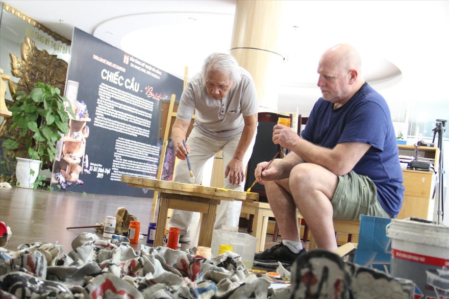 Nghệ sĩ Mark Cooper và họa sĩ Vũ Trọng Thuấn cùng nhau vẽ trên chất liệu gỗ chuẩn bị cho triển lãm “Chiếc cầu”. Ảnh: Thannh Trần 