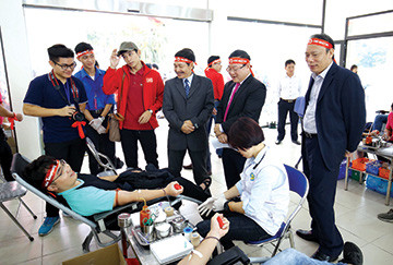 Nhà báo Lê Xuân Sơn - Tổng biên tập báo Tiền Phong (đứng thứ 2 từ phải sang) cùng PGS.TS Trần Văn Tớp, Phó hiệu trưởng Đại học Bách khoa Hà Nội (thứ 3 từ phải sang) thăm hỏi, động viên các sinh viên hiến máu tình nguyện