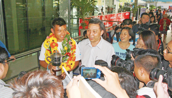 Lý Hoàng Nam trong vòng vây báo giới và người hâm mộ khi đặt chân xuống sân bay Tân Sơn Nhất cùng chiếc cúp vô địch đôi nam trẻ Wimbledon 2015. Ảnh: Ngô Tùng