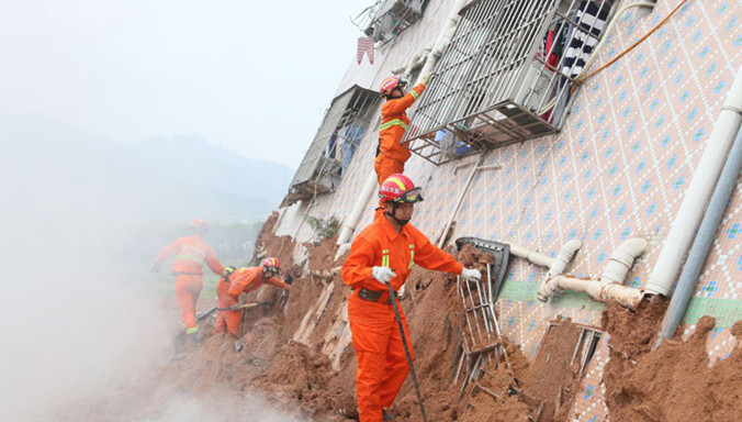 Tìm kiếm người mắc kẹt trong tòa nhà bị sập do lở đất. Ảnh: Xinhua