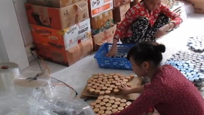 Hai nhân viên của một cơ sở làm mỹ phẩm nhái bị cơ quan chức năng phát hiện khi đóng gói. Ảnh: L.N