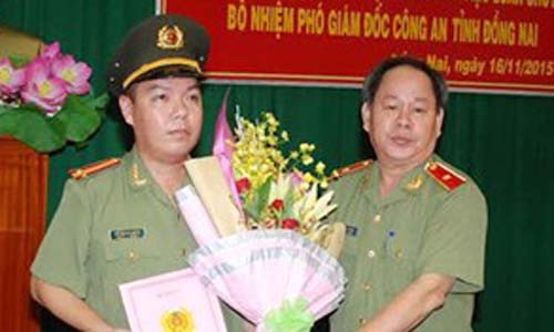 Thiếu tướng Nguyễn Thanh Nam (bìa phải) trao quyết định và tặng hoa chúc mừng Trung tá Lê Hoàng Ngân. Ảnh: Báo Đồng Nai 