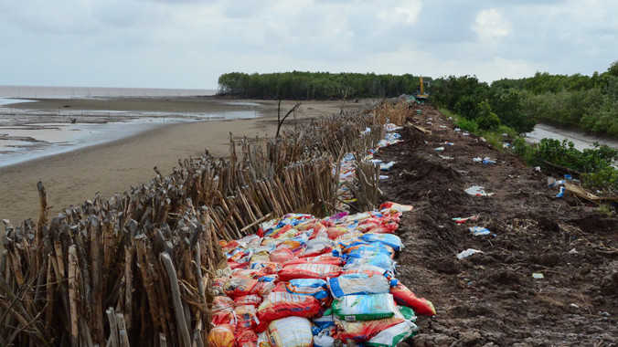 Một đoạn đê vỡ được gia cố bằng cừ tràm và bao đất.Ảnh: Xuân Lương