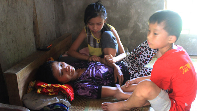 Hai con thơ vừa bóp chân tay cho mẹ vừa khóc, vì bố XKLĐ ở Angola vừa qua đời vì sốt rét, gia đình chưa có tiền đem thi thể về nước.