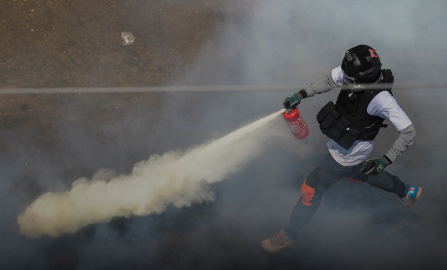 Một người biểu tình phun bình cứu hỏa khi đụng độ với cảnh sát chống bạo động ở Yangon ngày 28/2 Ảnh: Reuters 