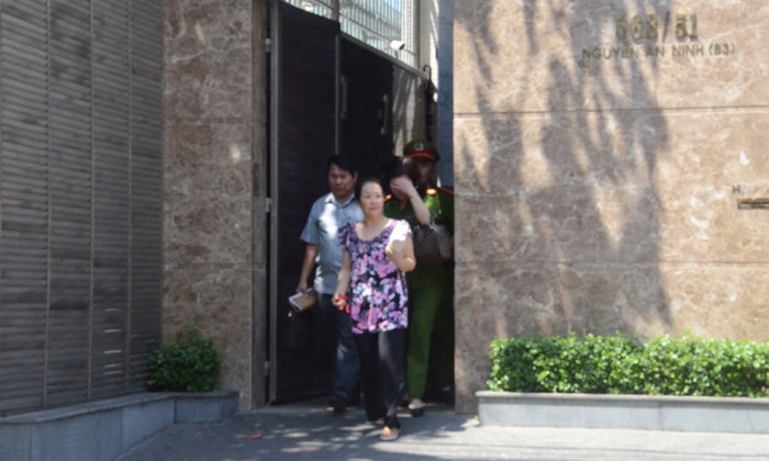 Bà Ngô Minh Phượng ( đi đầu tiên) được dẫn ra xe của cơ quan điều tra