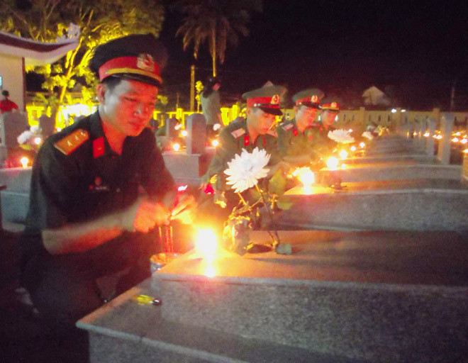 Các chiến sĩ Quân khu V thắp nến cho các phần mộ liệt sĩ. Ảnh: N.T