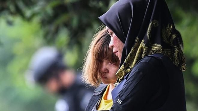 Chị Hương (phía sau) được cảnh sát dẫn giải. Ảnh: Getty