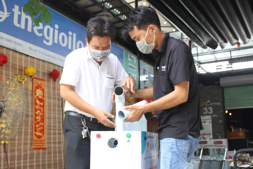 Anh Mai Anh Ðức (trái) thử nghiệm máy khử khuẩn di động. Vì máy biến dung dịch thành hơi sương siêu mịn nên không gây ướt quần áo khi khử khuẩn. Ảnh: Giang Thanh
