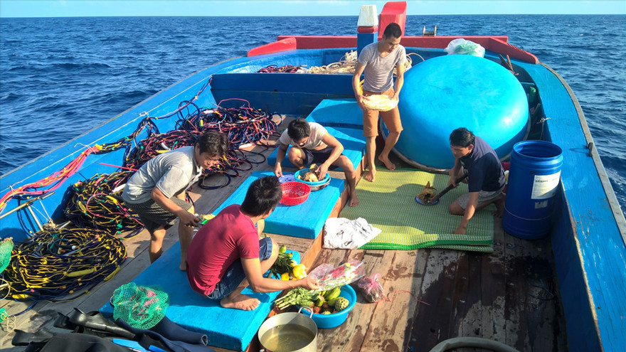 Ngư dân Nguyễn Đình Sang (áo đỏ) đang sắp mâm cúng trước giờ tàu chạy vào vòng Nguyệt Thiềm. Ảnh: Văn Chương 
