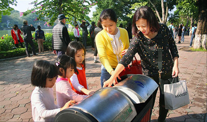 Hướng dẫn trẻ em bỏ rác đúng nơi quy định, dần hình thành văn hóa ứng xử nơi công cộng. Ảnh: Anh Tuấn.