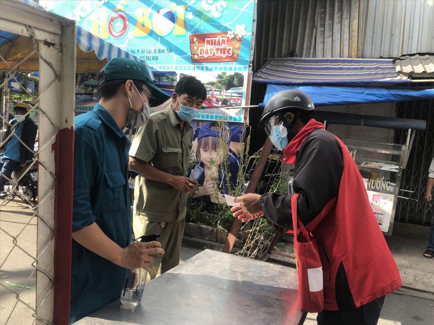 Người dân khu phong tỏa khi có chuyện khẩn cấp sẽ được xem xét cấp giấy ra khỏi chốt chặn Ảnh: U.P 