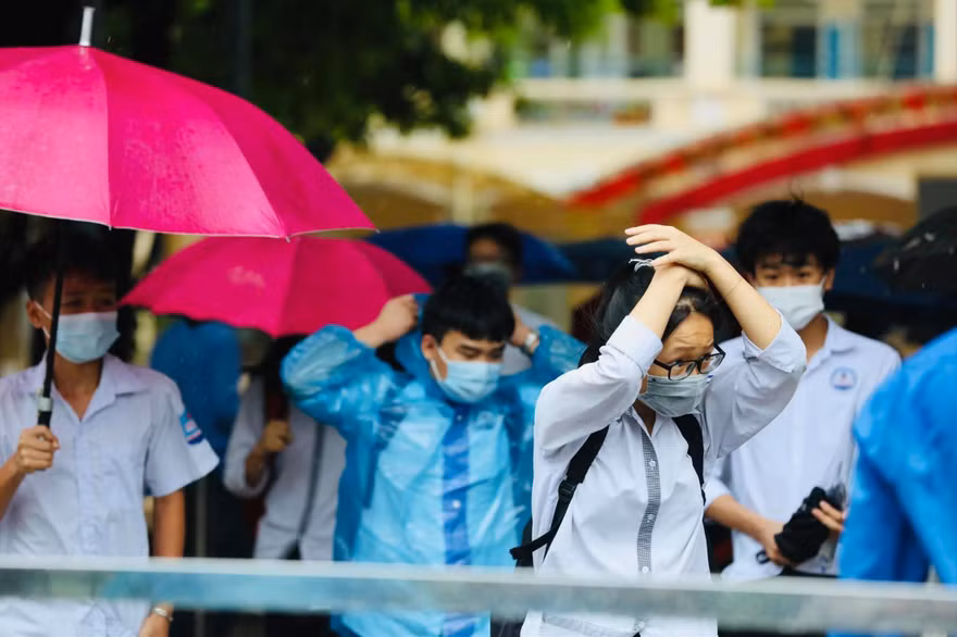 Thí sinh đội mưa đến điểm thi ở Hà Nội ngày 13/6. Ảnh: Như Ý 