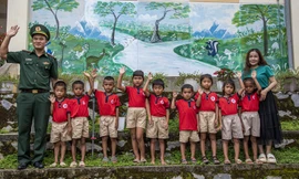 Các cháu học sinh, cô giáo và chú bộ đội chụp ảnh trước bức tranh khổ lớn do cô giáo Thảo vẽ Ảnh: Lê Văn Chương 