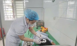 Bé H.T.N.L đang được bác sĩ thay băng vết thương do bị cha dượng bạo hành. Ảnh: HOÀI NAM