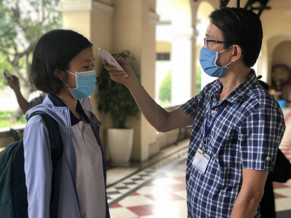 Thí sinh được đo thân nhiệt trước khi vào phòng thi. Thí sinh đeo khẩu trang, được đo thân nhiệt khi làm thủ tục thi tốt nghiệp THPT ảnh 1
