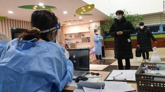 Thí sinh đứng cách xa nhau khi xếp hàng làm thủ tục trước khi vào phòng thi. Ảnh: CNN “Vượt vũ môn” giữa lúc dịch bùng phát, sĩ tử Hàn mặc đồ bảo hộ “full giáp” đi thi ảnh 5