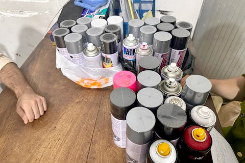 Các bình phun sơn được công an thu giữ.