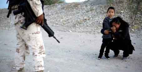 Người mẹ Guatemala cầu xin lính cho cô được vào Mỹ. Ảnh: Reuters