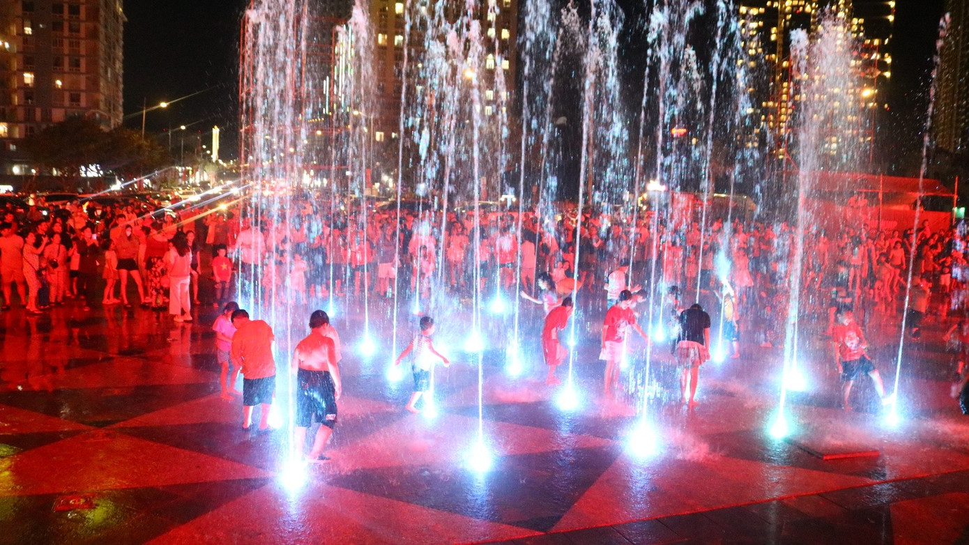 Trẻ con chơi đùa, tắm mát tại khu vực phun nước cạn trước tháp Tam Thắng tối ngày 30/8. Ảnh: Hoàng Nhân.