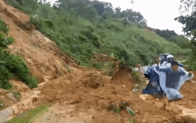 Nhóm người tháo chạy khi sạt lở đất đá đổ xuống đường.