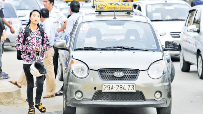 Tem dán trắng ở kính xe nhưng taxi vẫn đứng hàng ngang bắt khách trên đường Nguyễn Trãi, Hà Nội. Ảnh: Như Ý