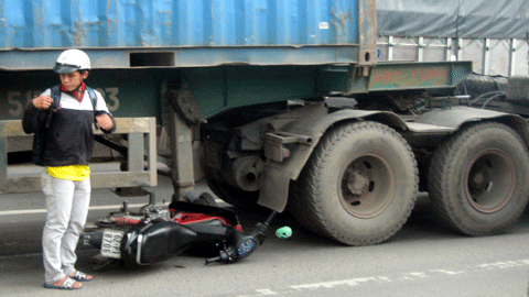 Chiếc xe máy nằm gọn dưới gầm xe container nhưng nạn nhân đã may mắn thoát nạn.