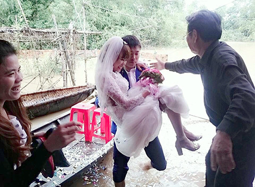 Bước xuống thuyền, chú rể xắn quần bế cô dâu qua đoạn nước ngập vào tổ chức lễ cưới trong sự cổ vũ của mọi người. Ảnh: Đ.H.