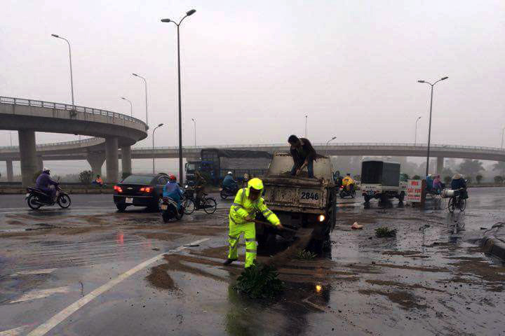 Lực lượng CSGT xúc cát rải lên vết dầu loang trên đường.