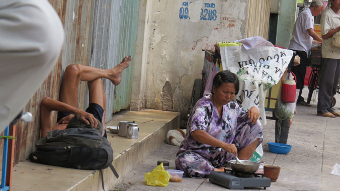 Bà Phượng đang nấu cơm cho ông Chung ngay trên vỉa hè đường Nguyễn Chí Thanh.