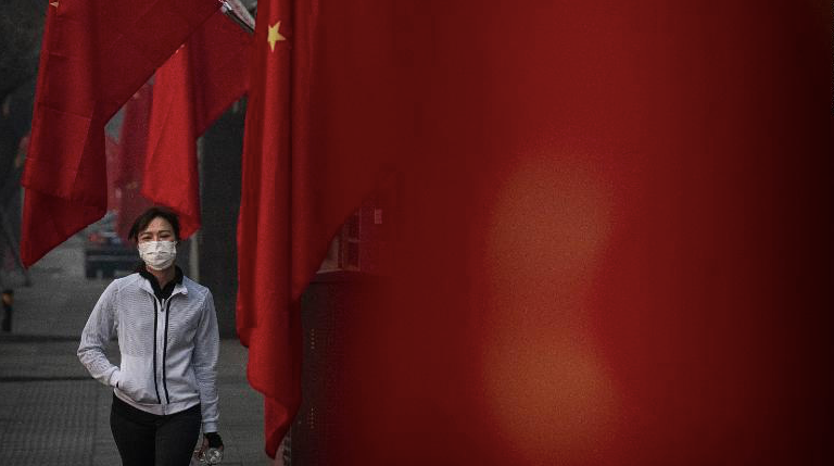 Một phụ nữ đeo khẩu trang khi đi bộ ở Bắc Kinh dịp Tết âm lịch vừa qua. (Ảnh: CNN)